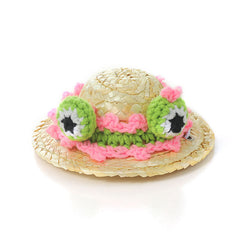 The straw hat is decorated with pink knitted frog eyes.